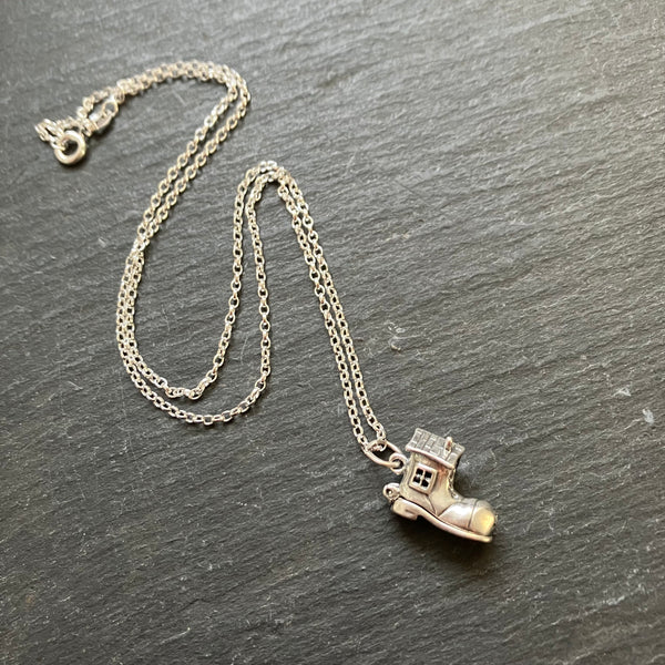 Silver necklace with a boot-shaped pendant on a dark surface